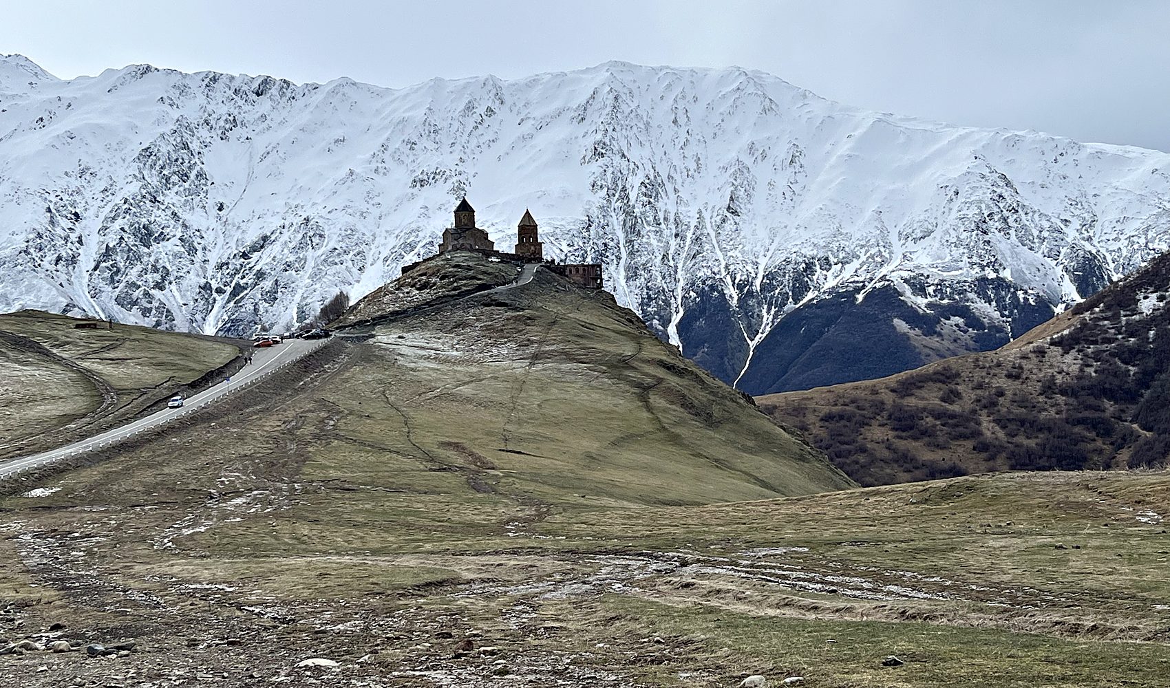 gergeti trinity church perched beneath the snow-covered wall of the greater caucasus