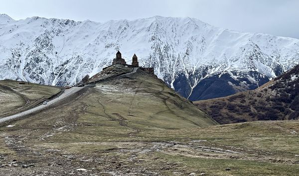 gergeti trinity church perched beneath the snow-covered wall of the greater caucasus